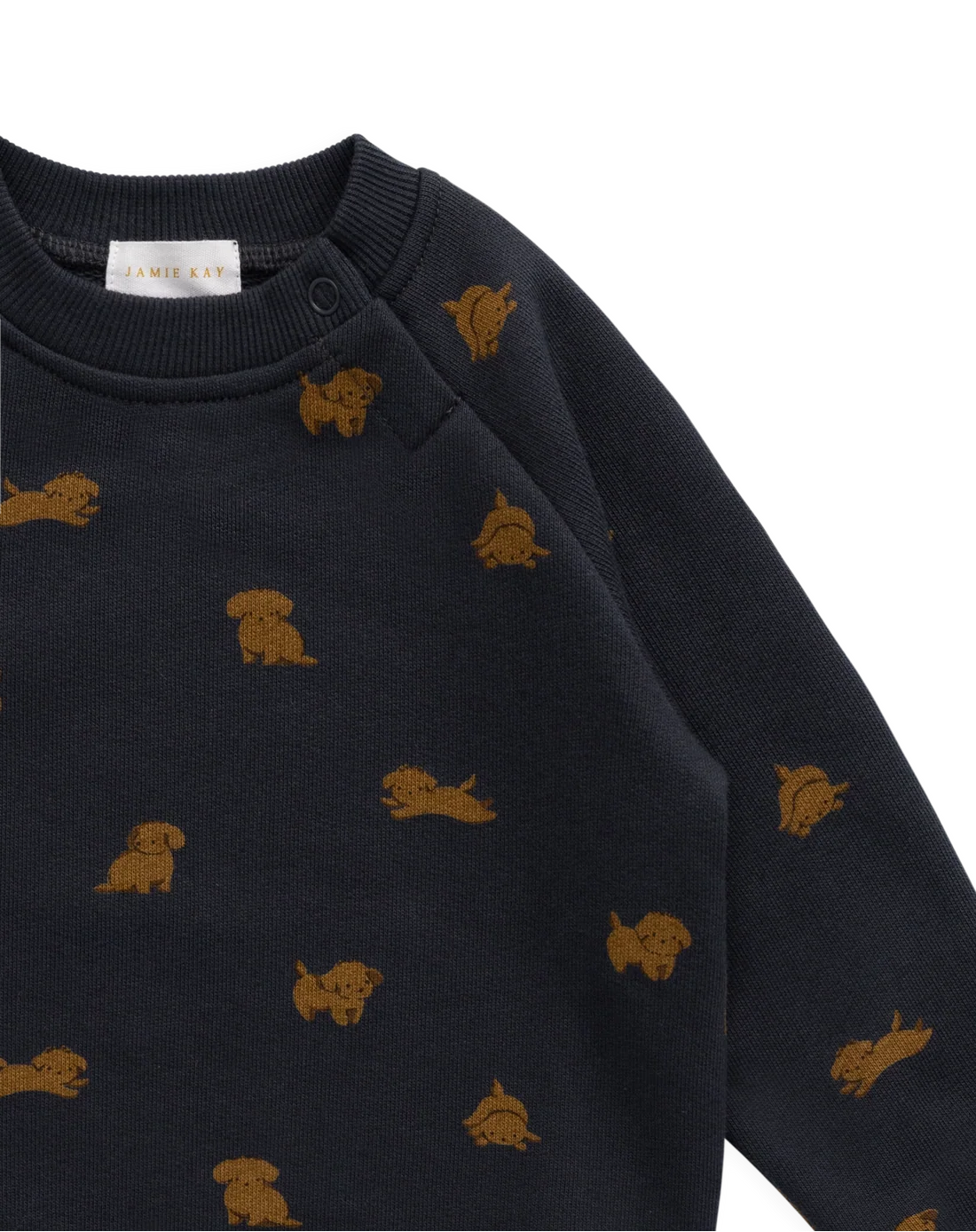 Close-up of a dark navy long-sleeve knit top with small mustard-gold dog motifs repeated across the fabric, shown on a plain white background.