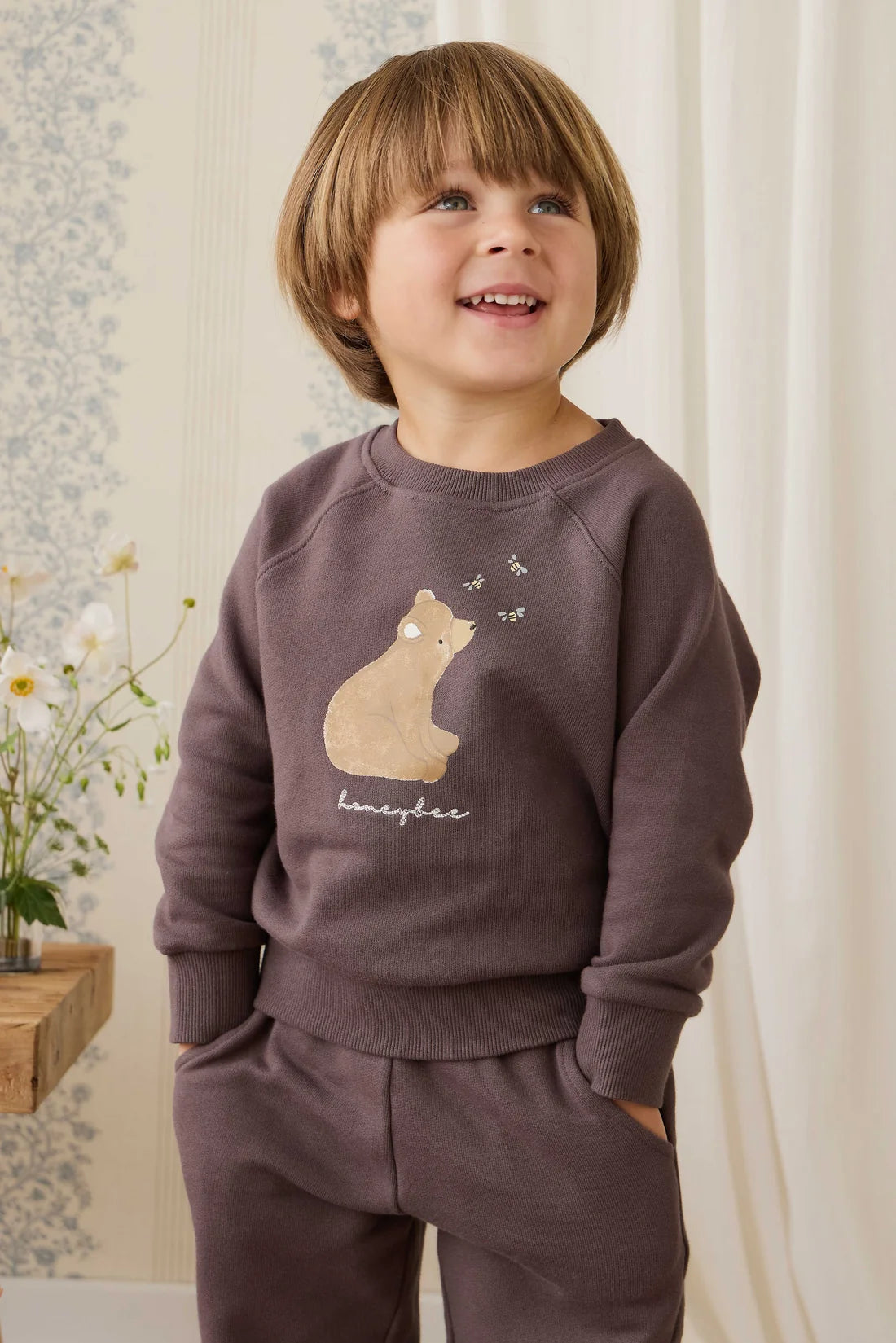 Child wearing a brown sweatshirt with a cat design in a home setting