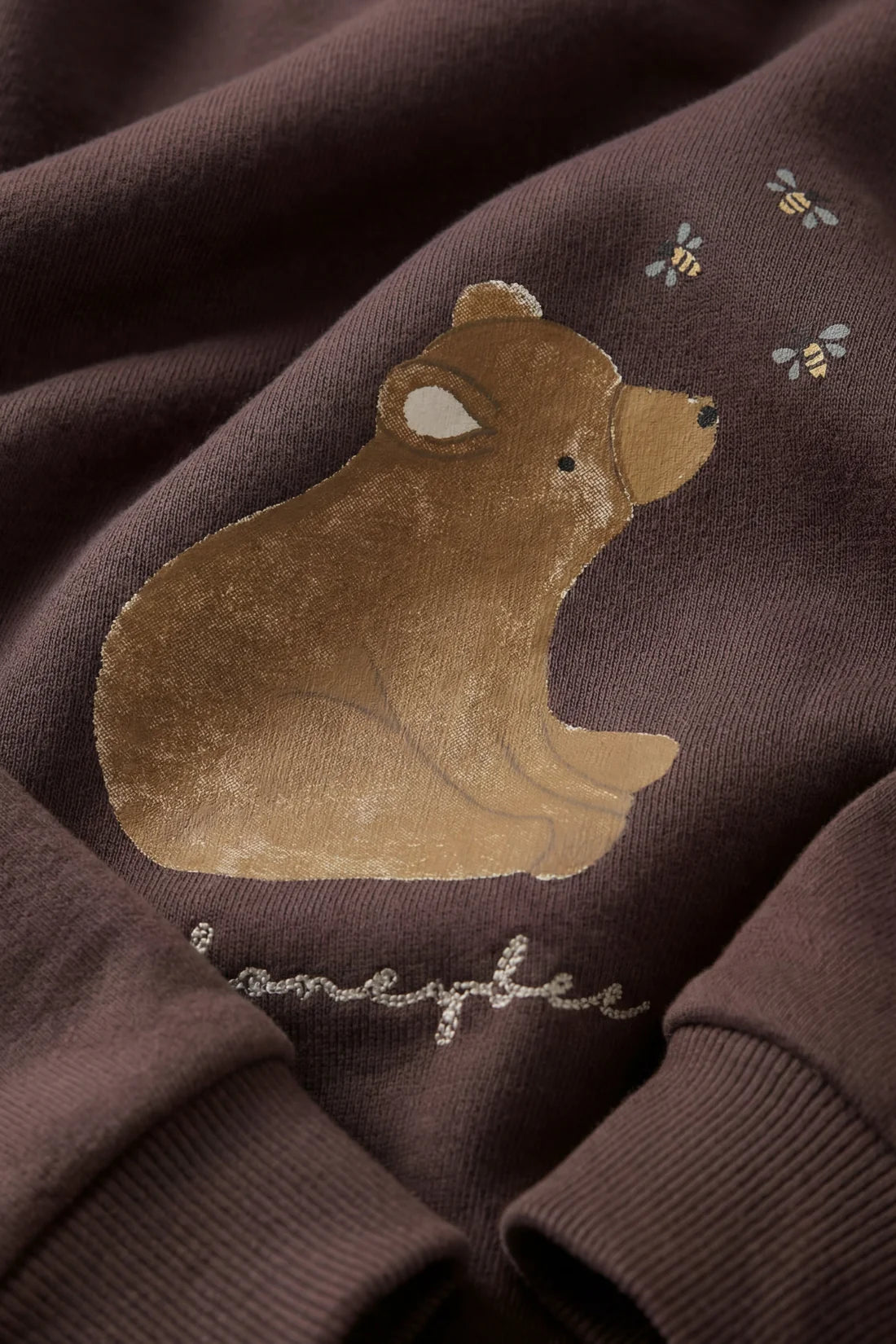 Brown bear with 'Honeybee' text on a brown fabric background