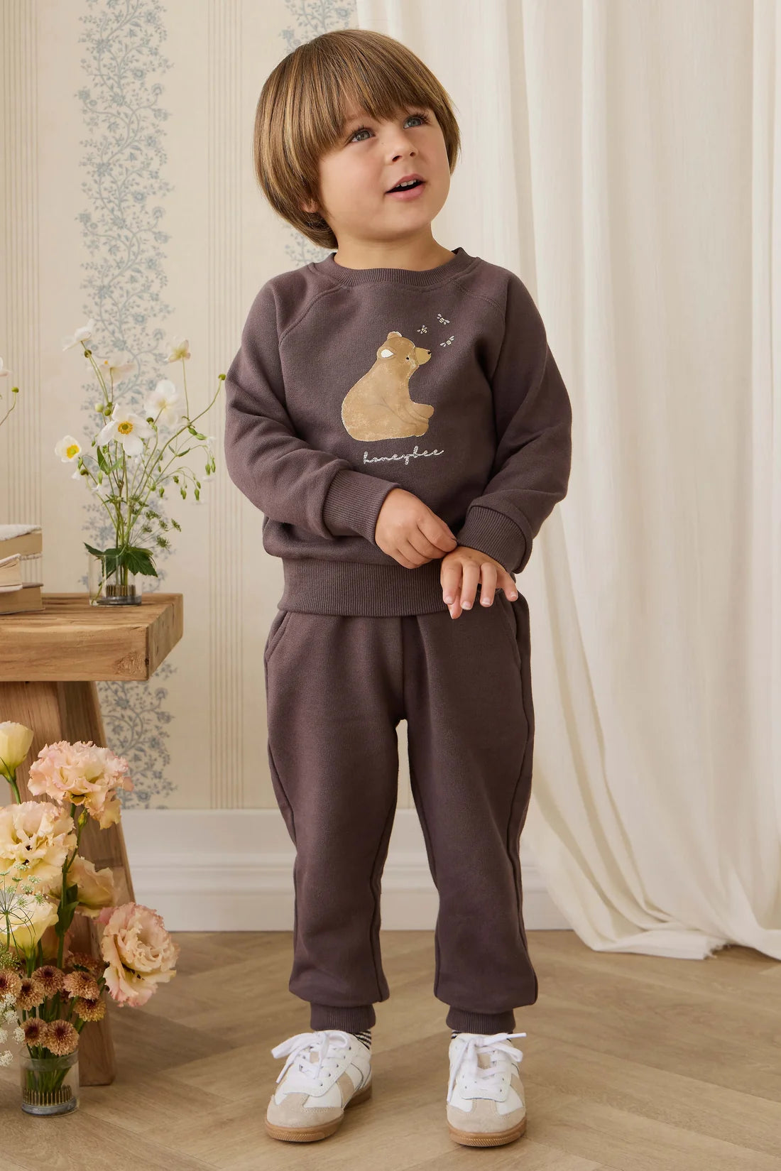 Child wearing a brown outfit with a bear design in a home setting