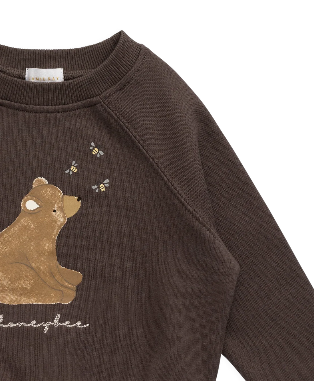 A close-up of a dark brown crewneck sweatshirt featuring a graphic of a brown bear and three small bees, with the word 'honeybee' written in white script below.