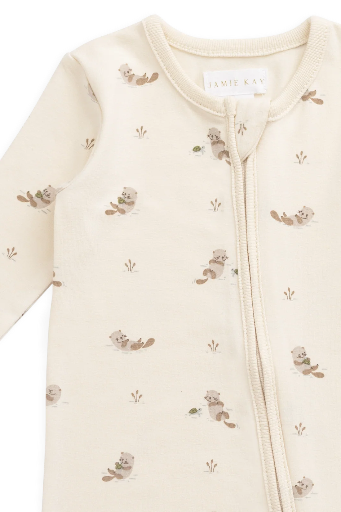 A close-up of a baby sleep sack by Jamie Kay, featuring a cream-colored fabric with a repeating pattern of small brown beavers and tiny tufts of grass, complete with a front zipper.