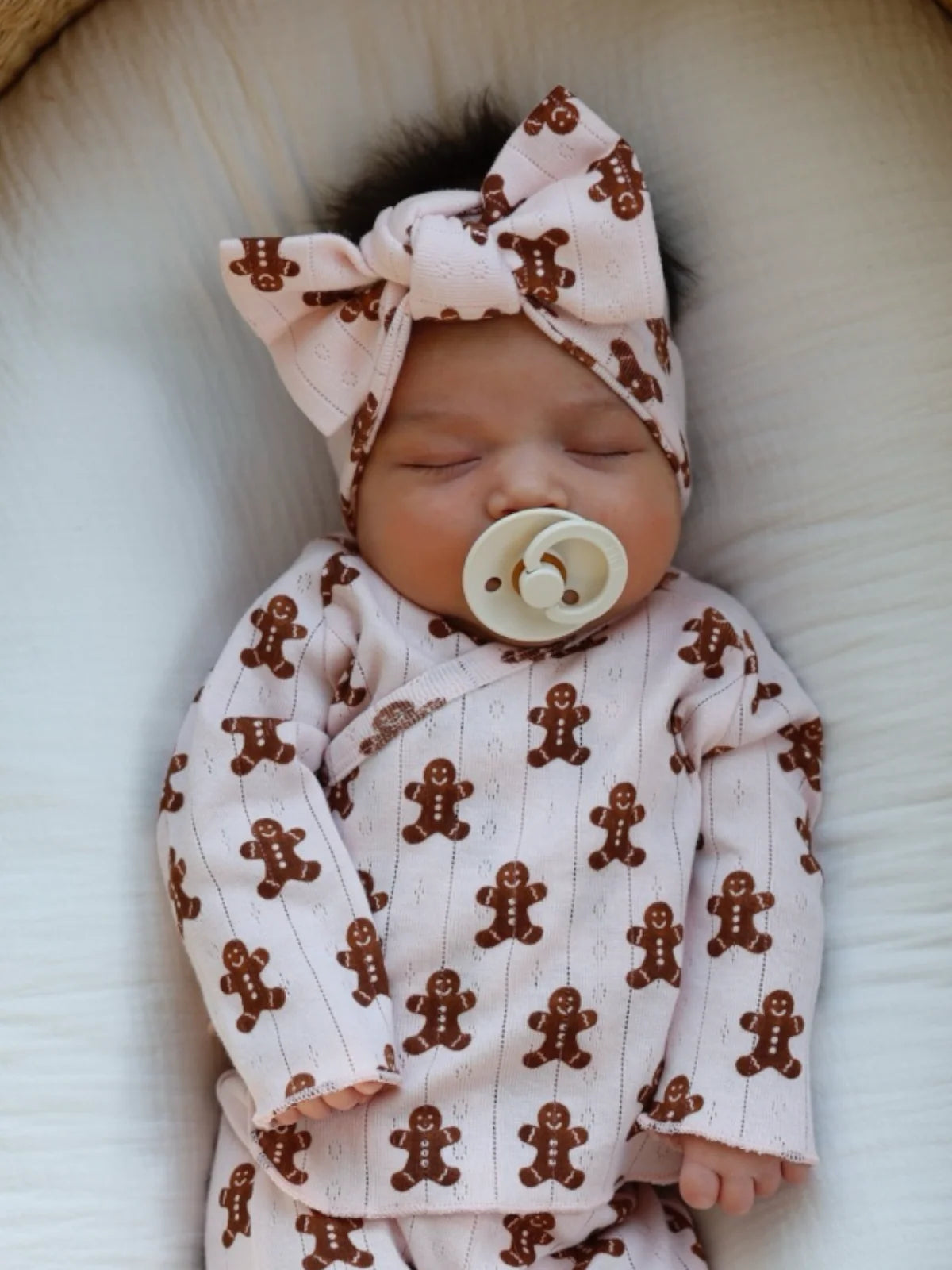 Baby wearing a gingerbread-themed outfit with a matching headband and pacifier.