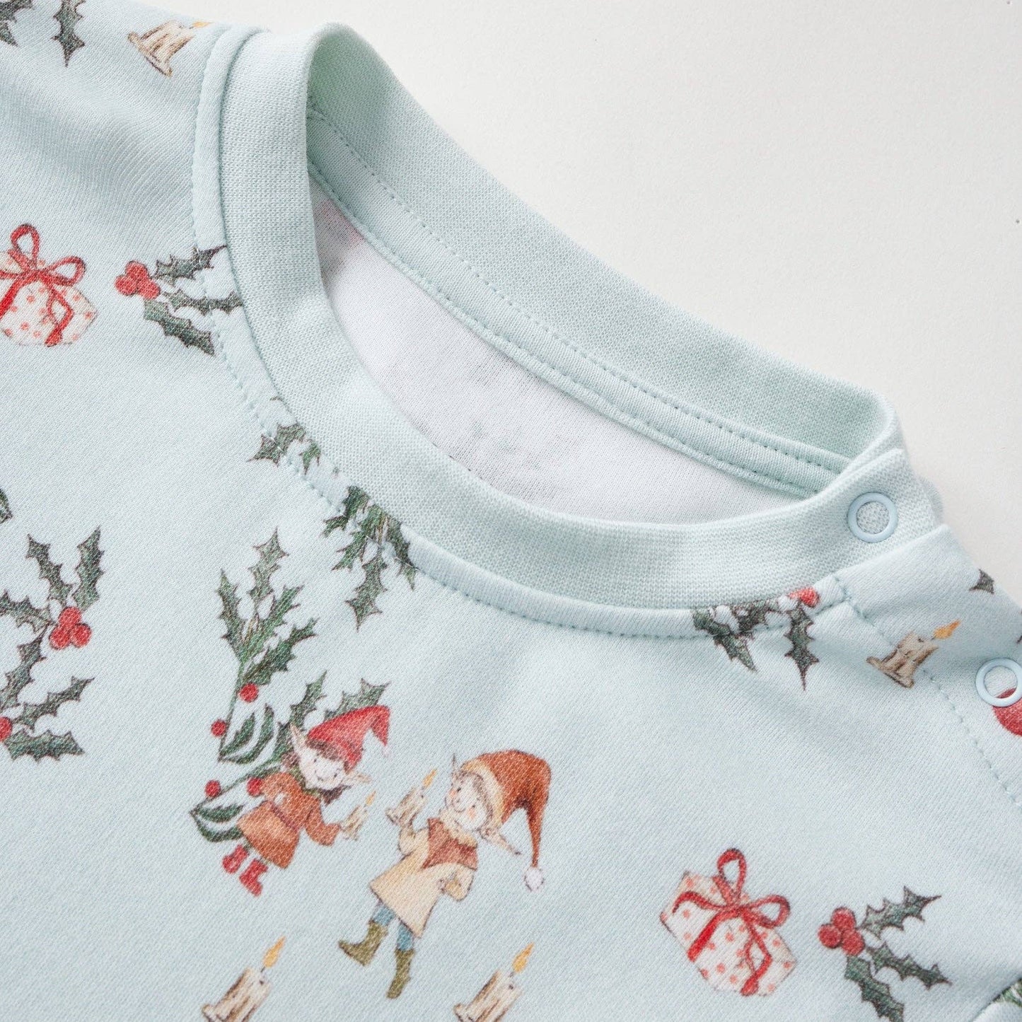 Baby onesie with Christmas-themed print on a light blue background