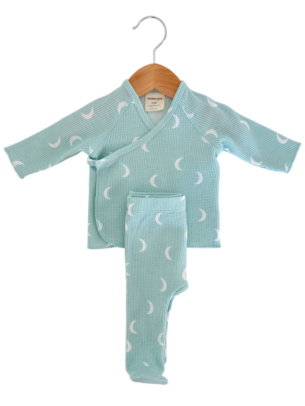 Baby outfit with long-sleeve top and pants on a hanger against a white background