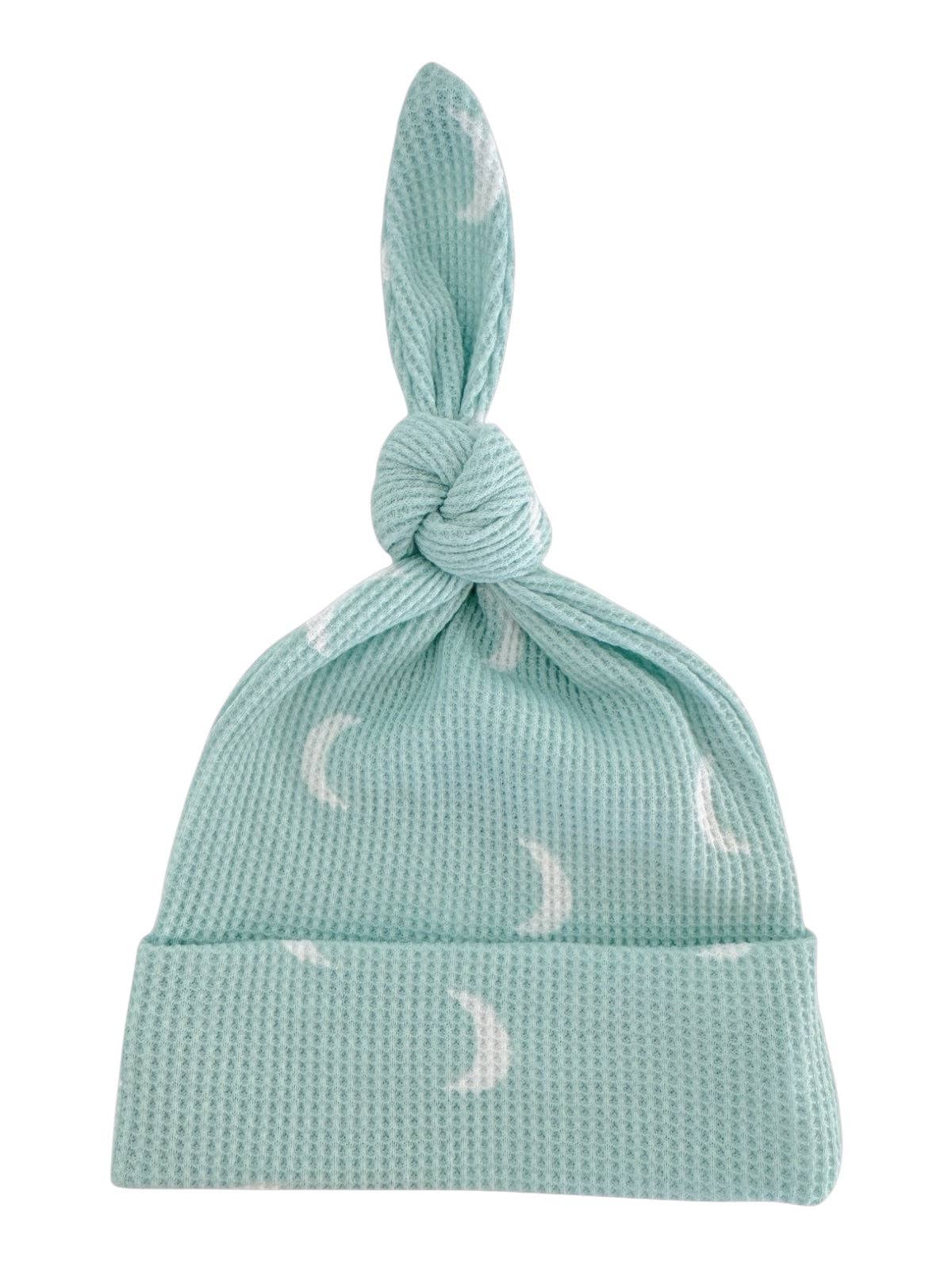 Light blue baby hat with moon pattern on a white background