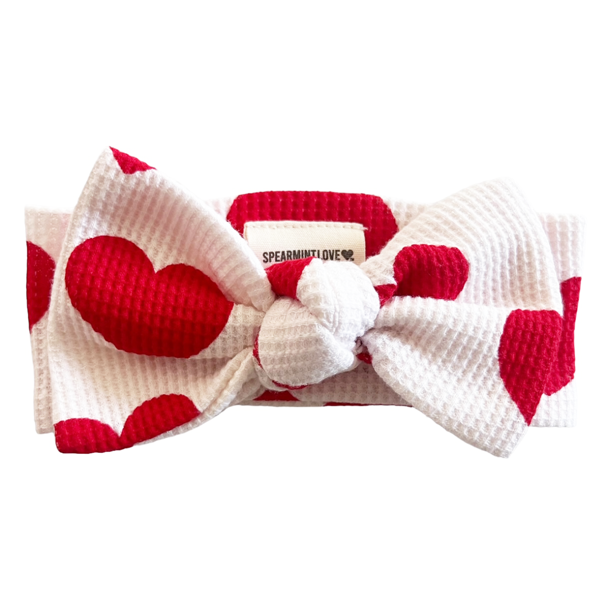 Red and white heart-patterned headband with a bow on a white background
