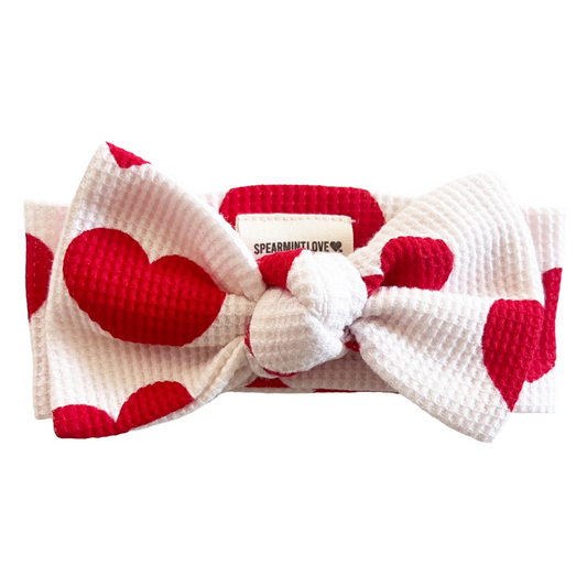 Red and white heart-patterned headband with a bow on a white background