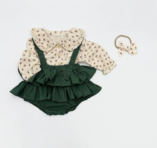 Green ruffled romper with floral blouse and hair bow on a white background
