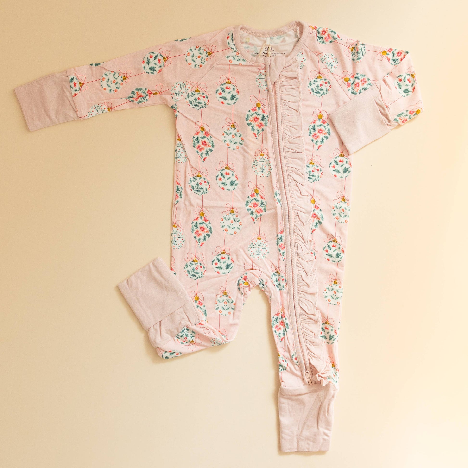 Floral-patterned baby onesie on a beige background
