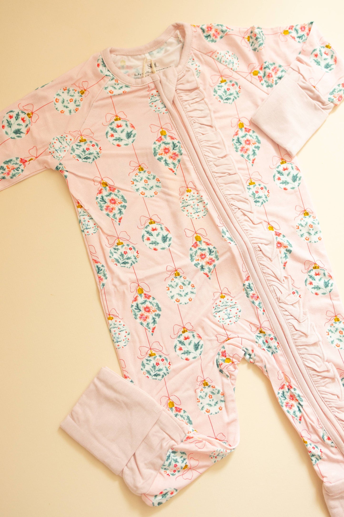 Pink floral baby romper on a beige background
