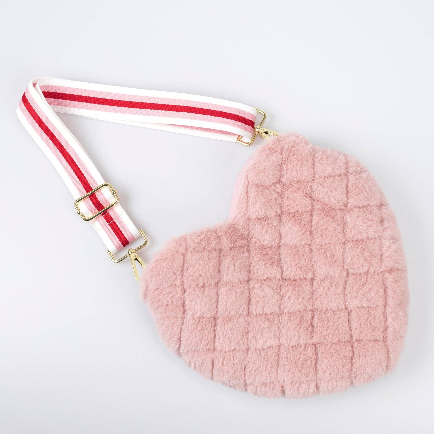 Heart-shaped pink pouch with a striped strap on a light gray background