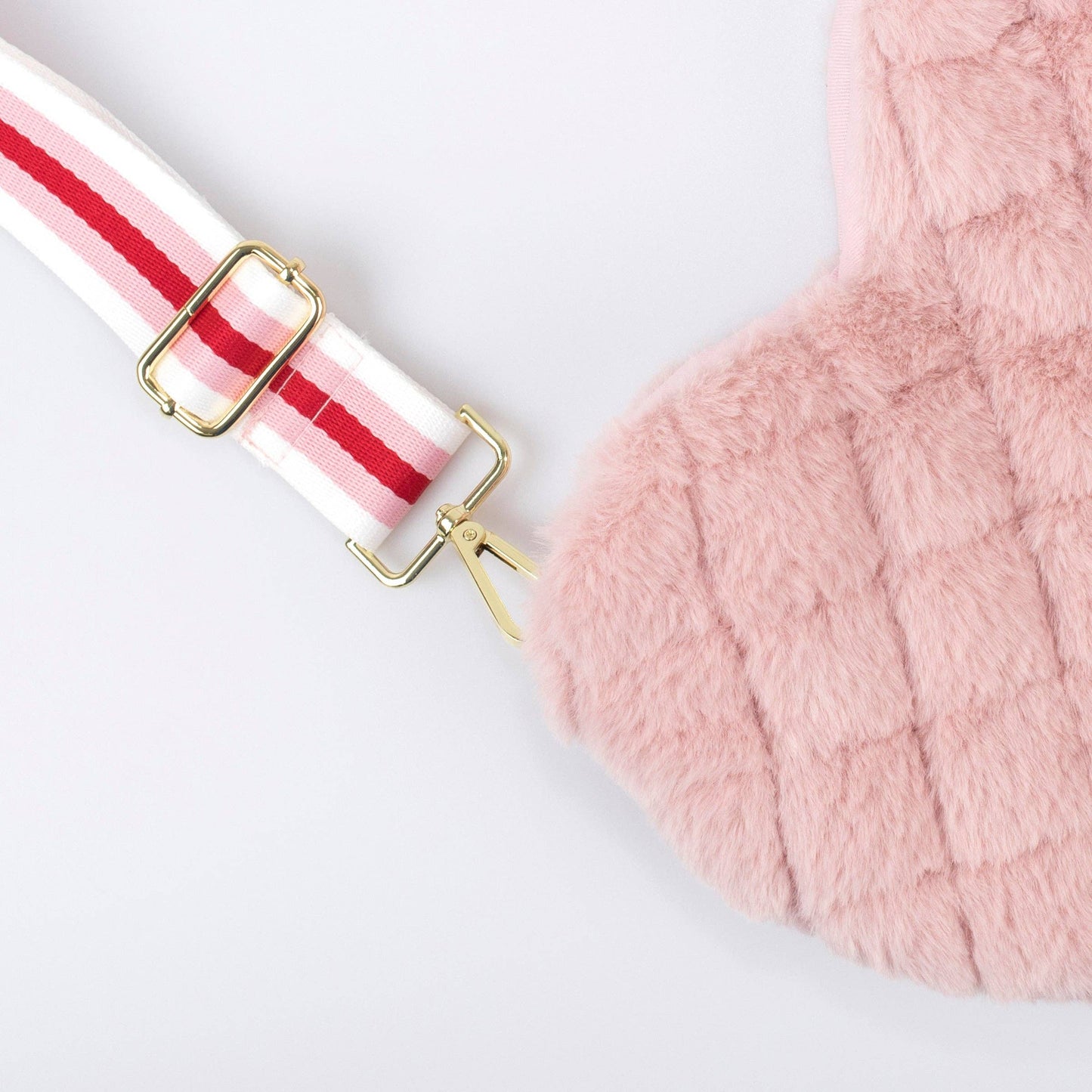 Close-up of a pink fluffy bag with a red and white striped strap on a light gray background