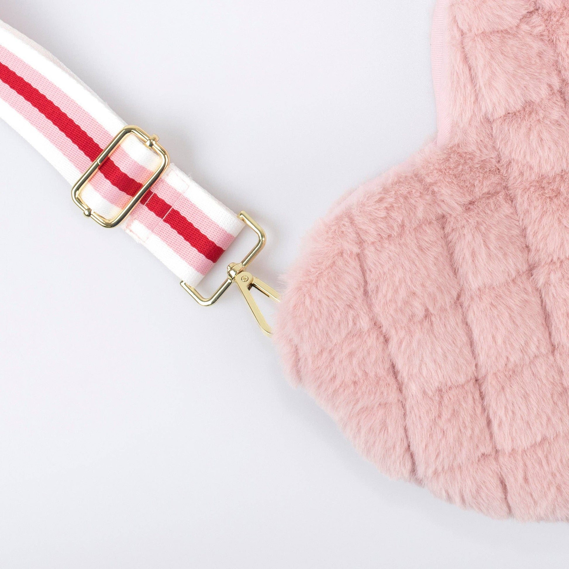 Close-up of a pink fluffy bag with a red and white striped strap on a light gray background