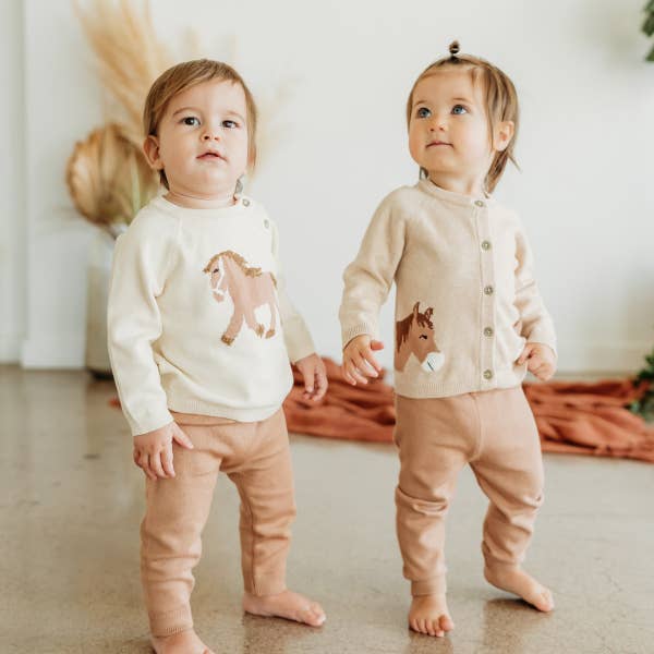 Two children wearing matching outfits with horse designs indoors.