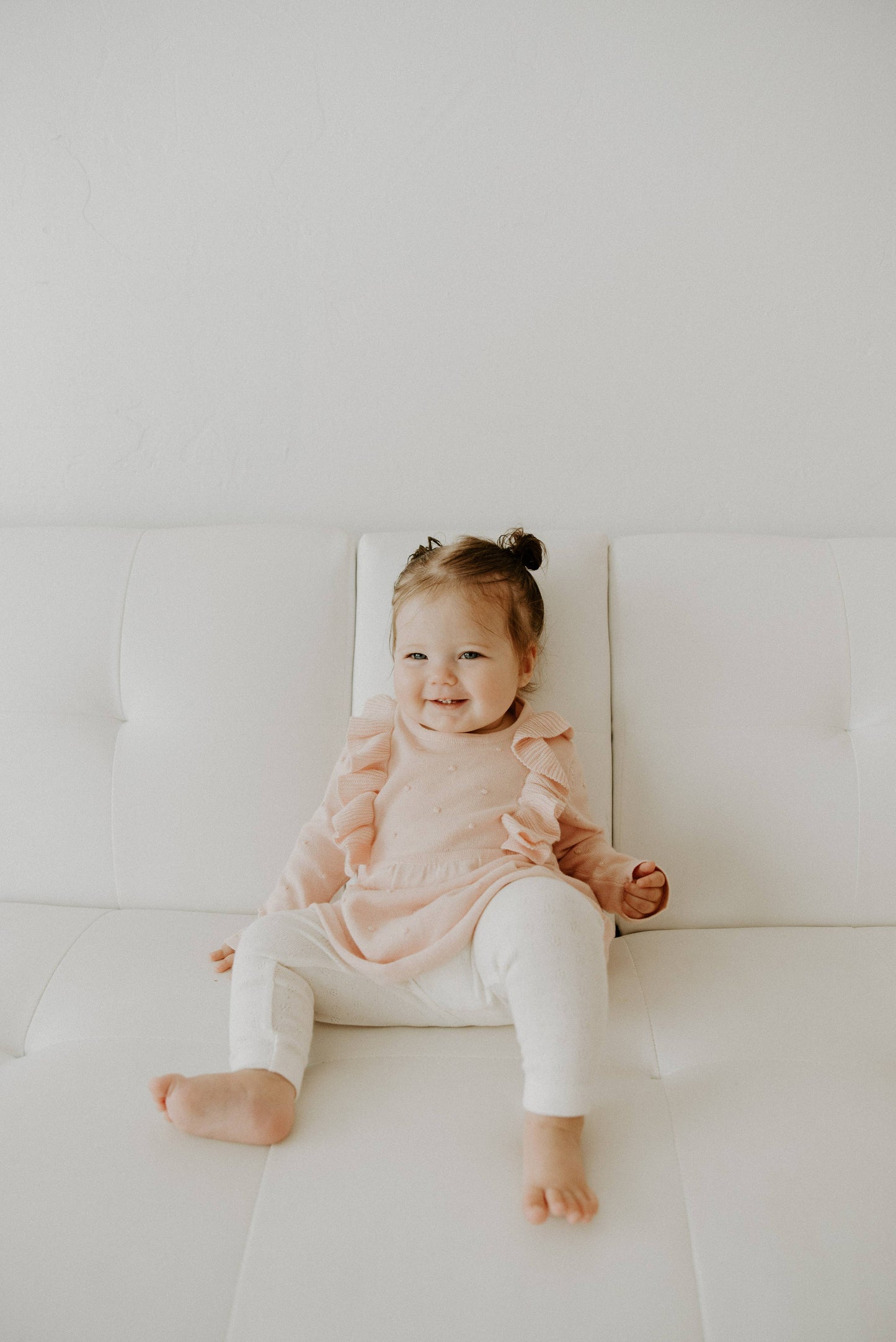 Child sitting on a white couch with a plain background