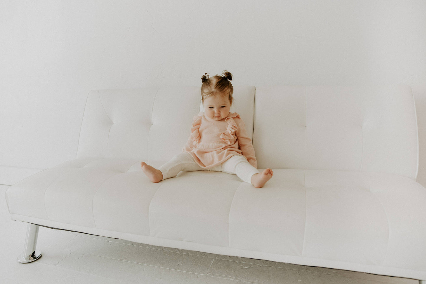 Child sitting on a white couch in a minimalistic room