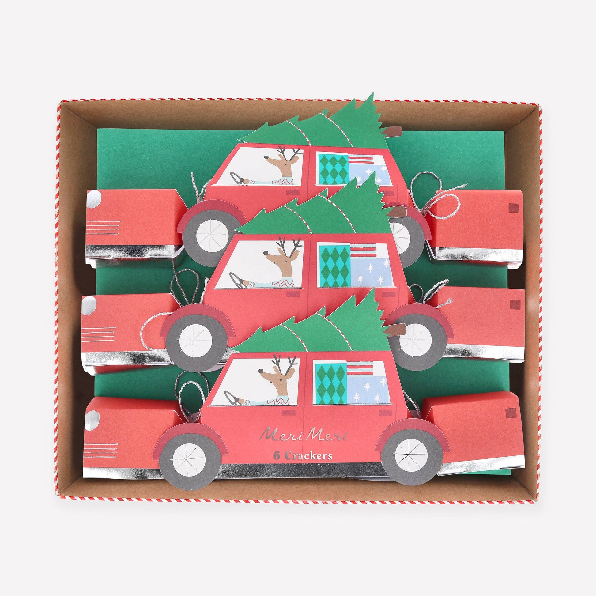Box of red car-shaped Christmas cards with green trees and deer on a white background