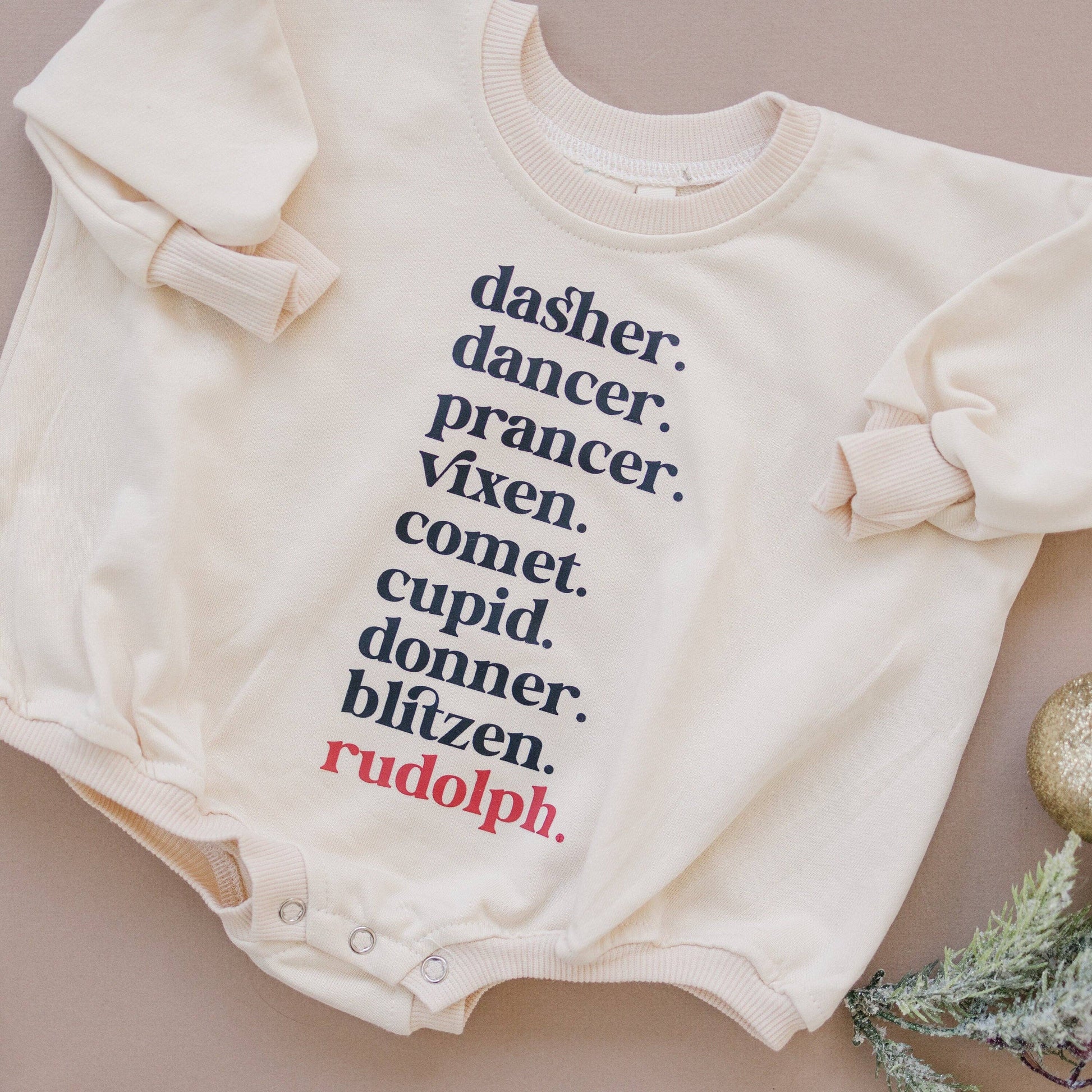 Baby onesie with Christmas-themed words on a beige background