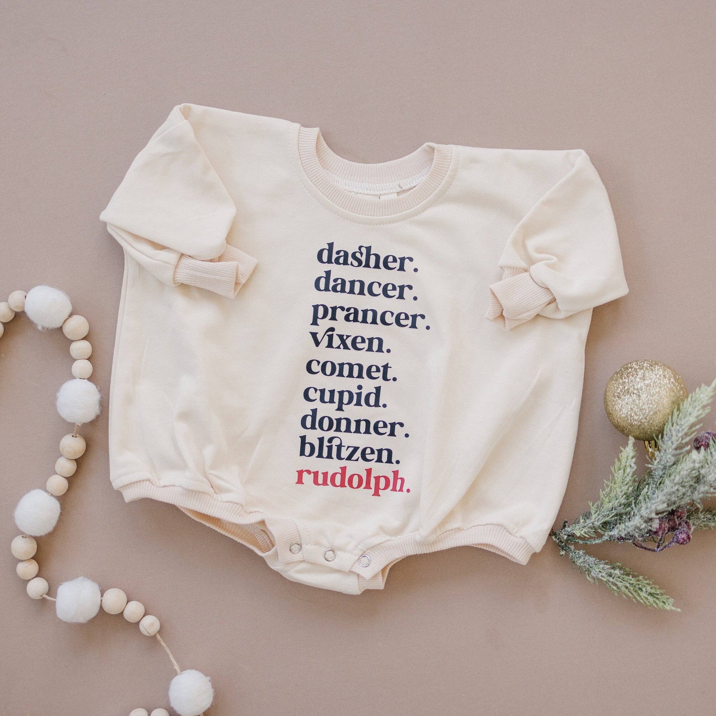 Baby onesie with Christmas-themed text on a beige background