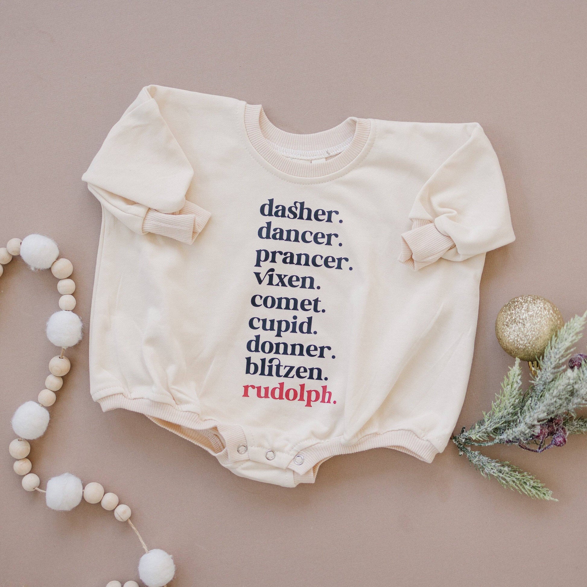 Baby onesie with Christmas-themed text on a beige background