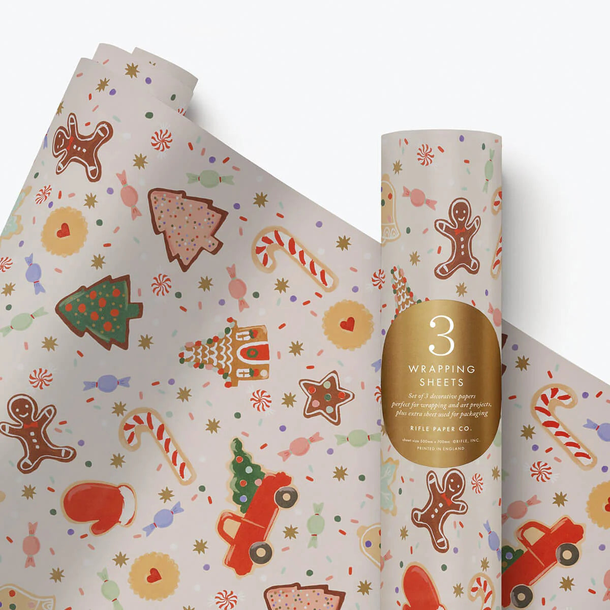 Roll of festive wrapping paper with gingerbread men, candy canes, and other holiday-themed designs on a white background.