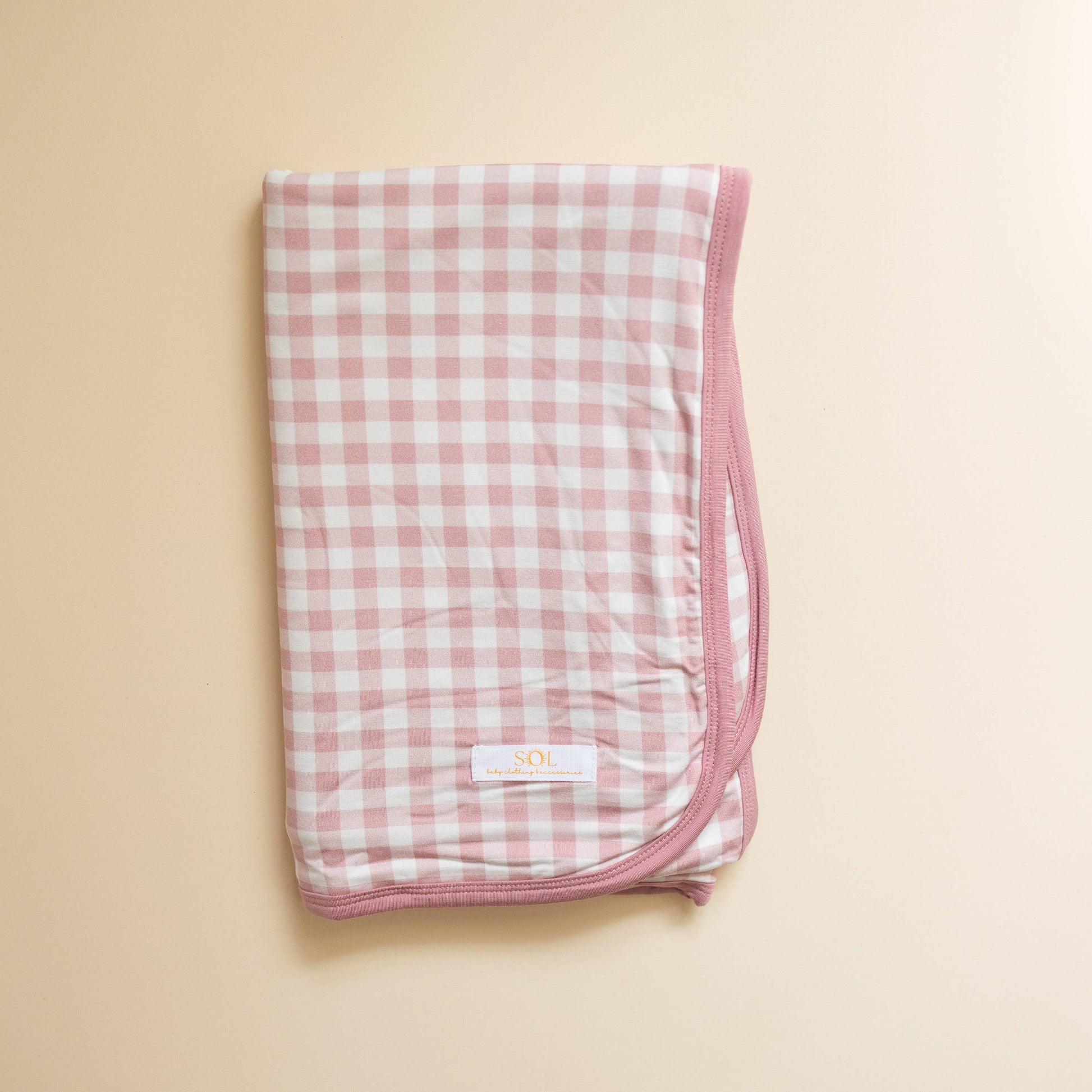 Folded pink and white checkered blanket on a beige background