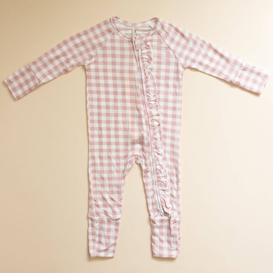 Pink gingham baby onesie on a beige background