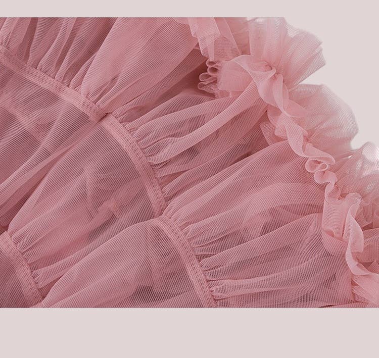 Close-up of a pink tulle fabric with ruffled edges on a light gray background
