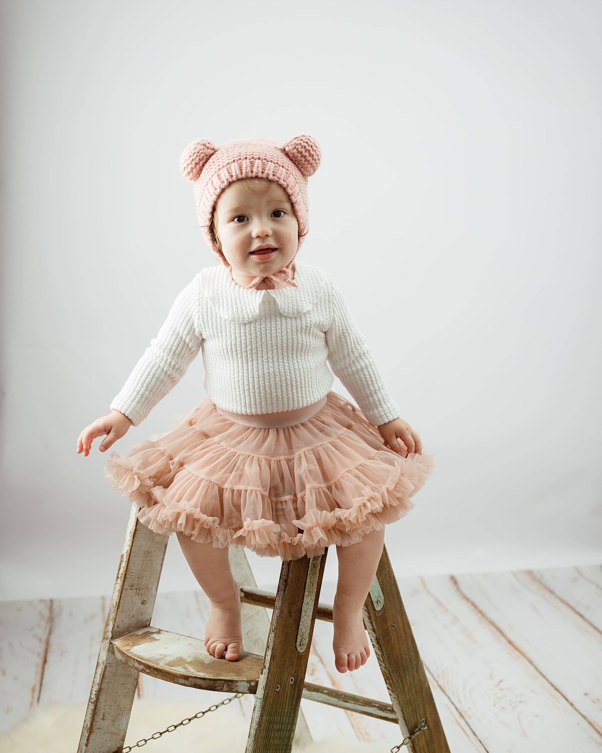 Child wearing a pink outfit with a white background