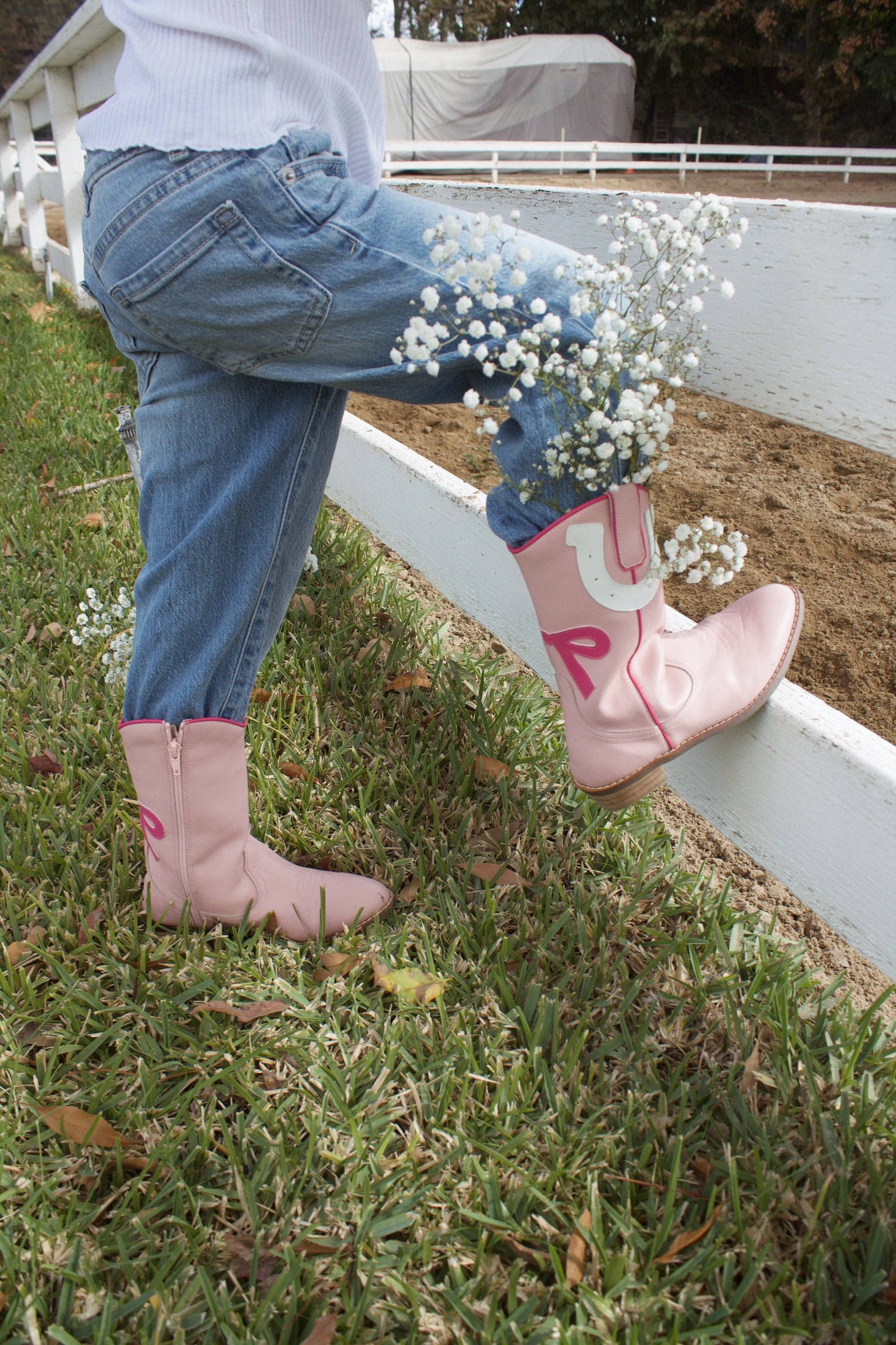 Person wearing pink cowboy boots with '1 UP' on a grassy area.