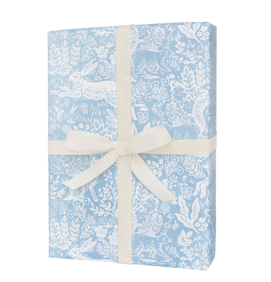 Gift box with blue floral pattern and white ribbon on a white background