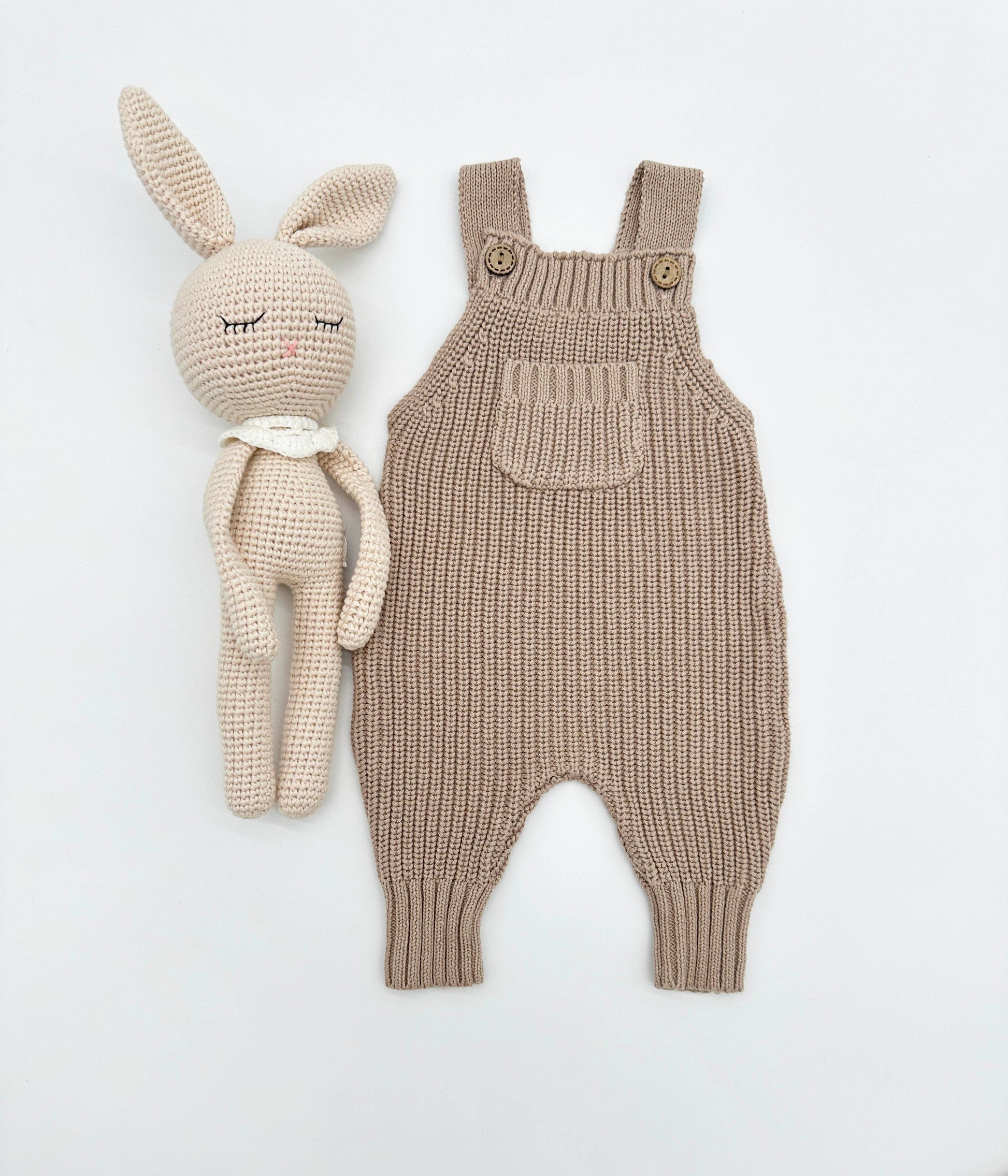 Knitted beige baby romper and toy rabbit on a light gray background