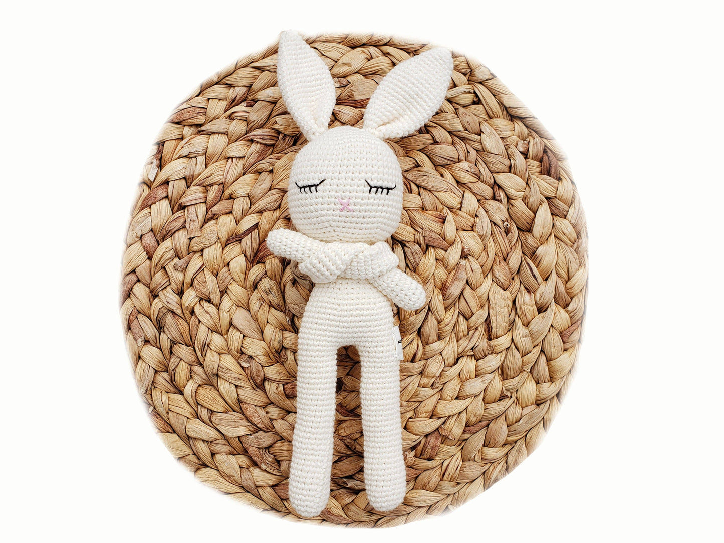 White rabbit-shaped plush toy on a woven mat