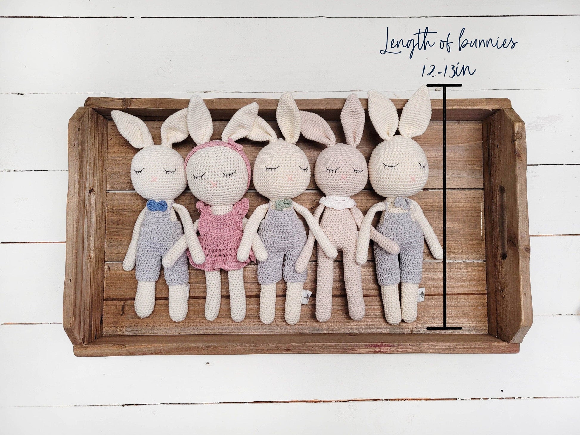 Set of crocheted bunnies in various outfits on a wooden tray with measurement details.