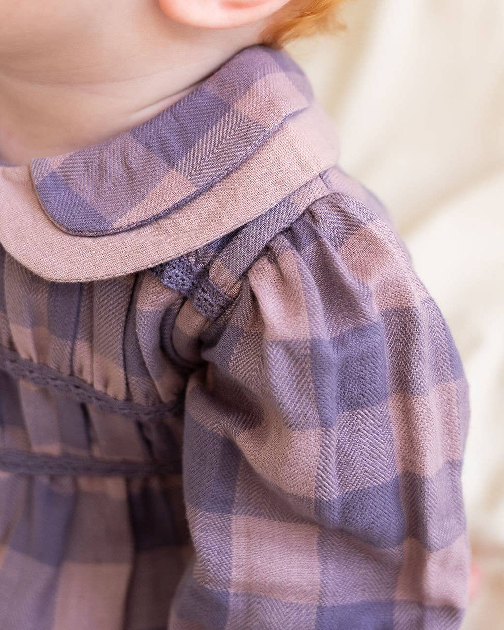 Close-up of a plaid garment with a collar, focusing on texture and pattern.