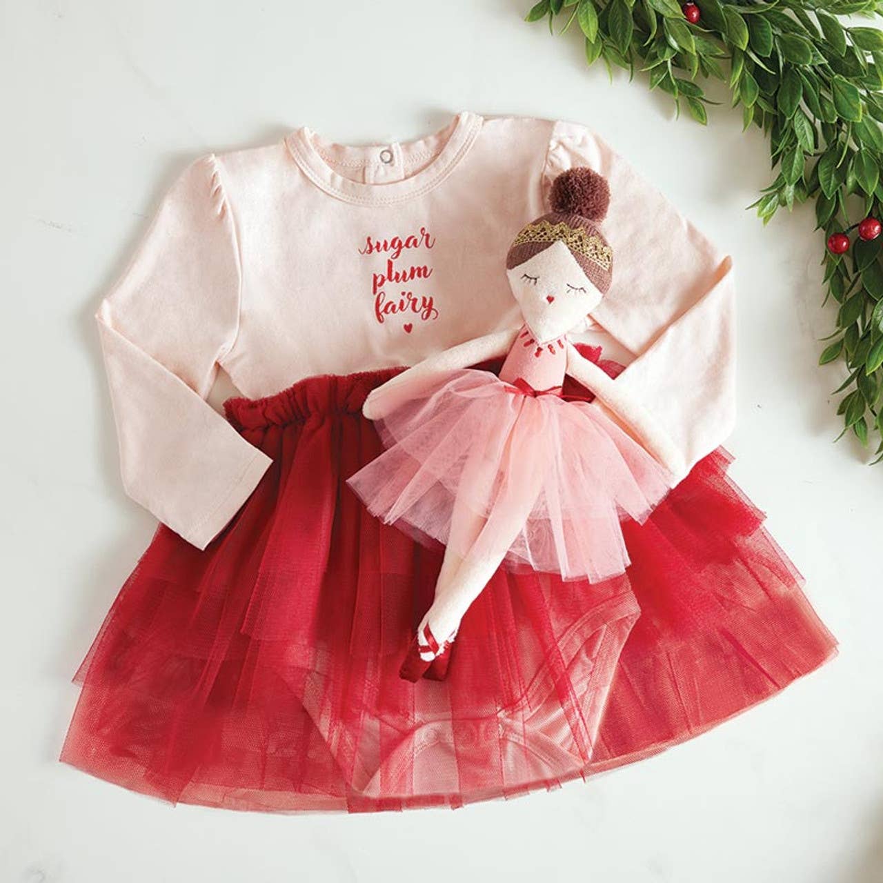 Children's dress with red tulle skirt and pink top featuring a doll, on a light background.