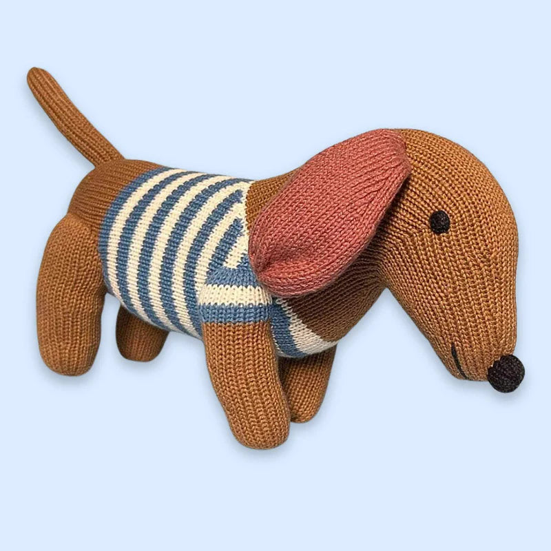 Knitted dachshund toy wearing a striped sweater on a light blue background