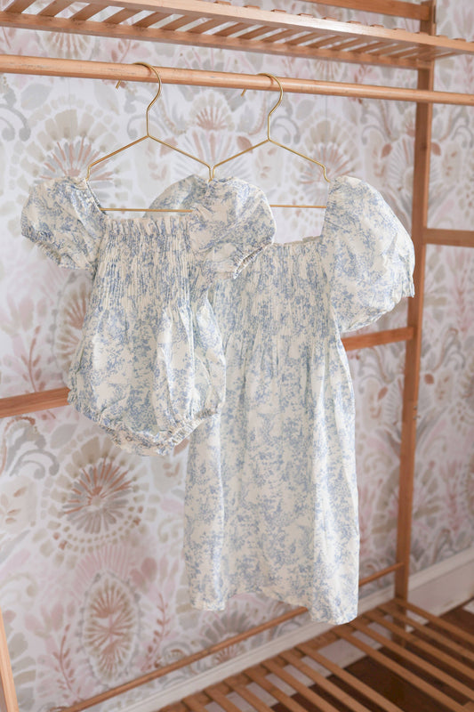 Floral dress hanging on a rack against a patterned wall