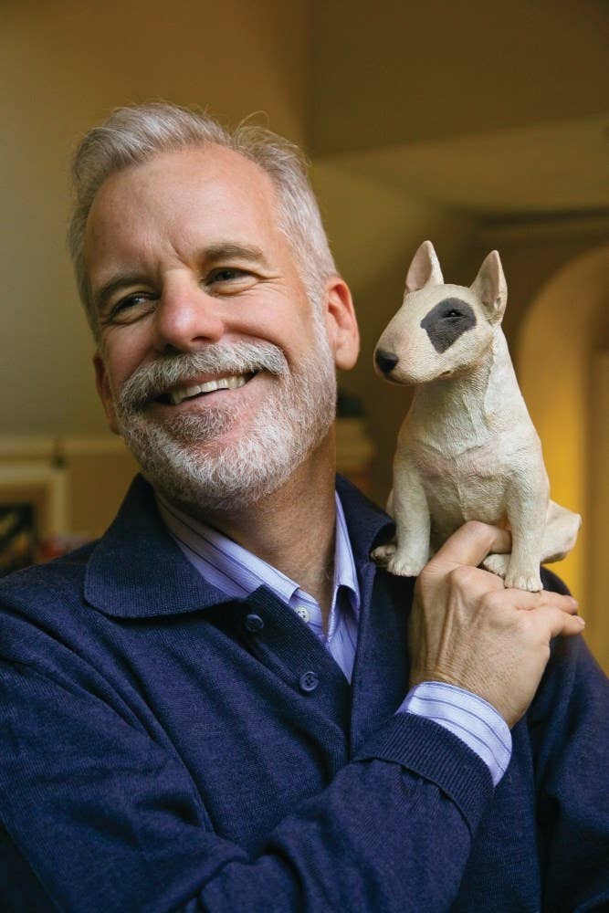 Man holding a small dog sculpture indoors