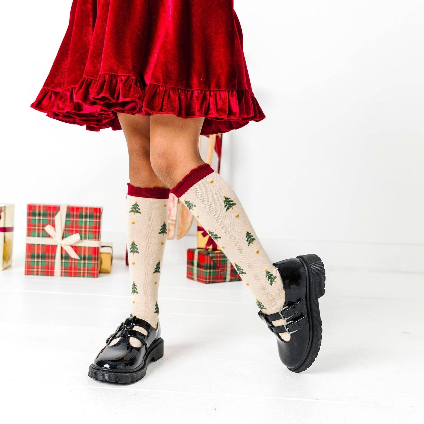 Person wearing a red skirt and black shoes with Christmas-themed tights on a white background.