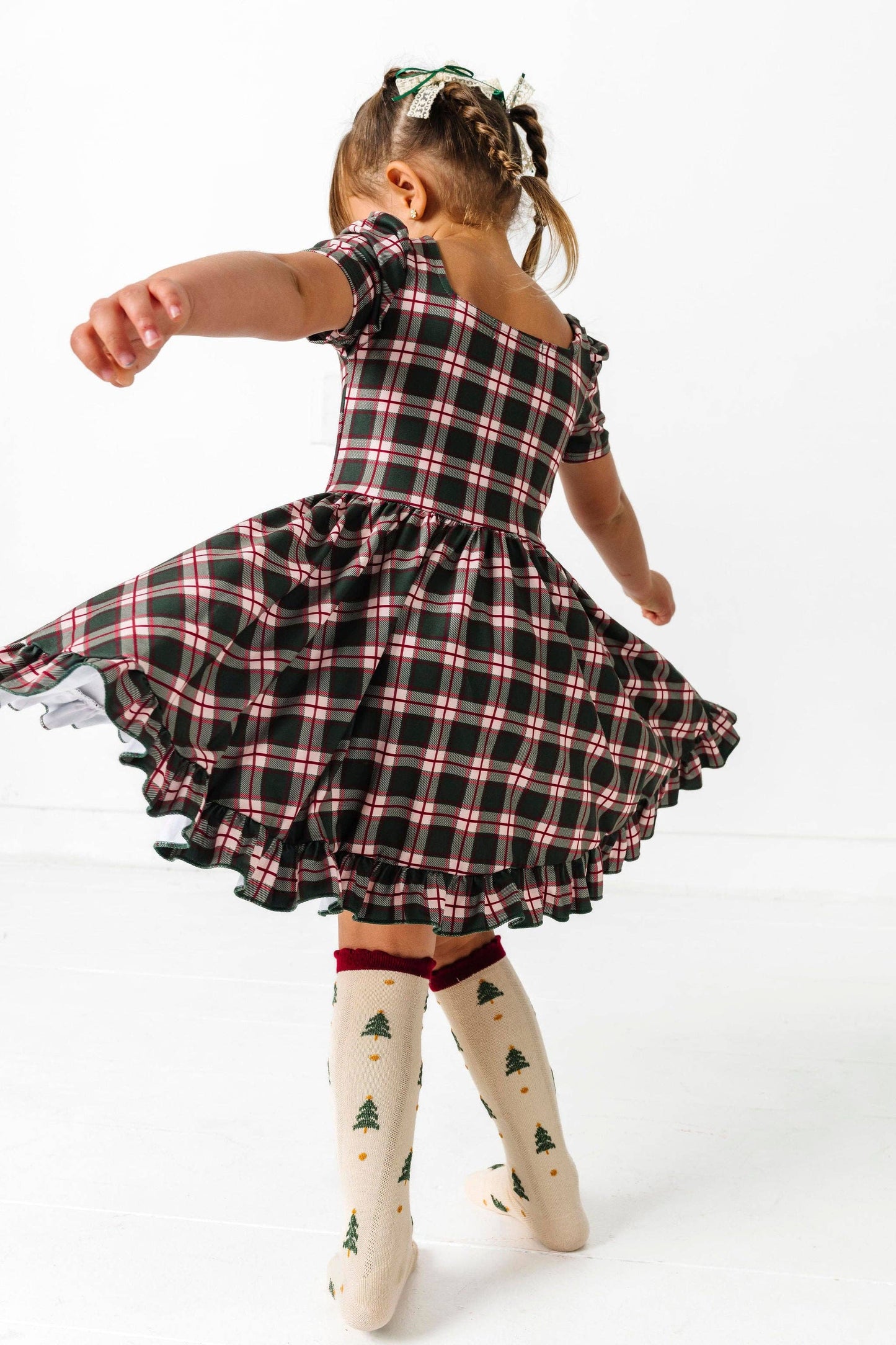 Child wearing a black and pink plaid dress on a white background
