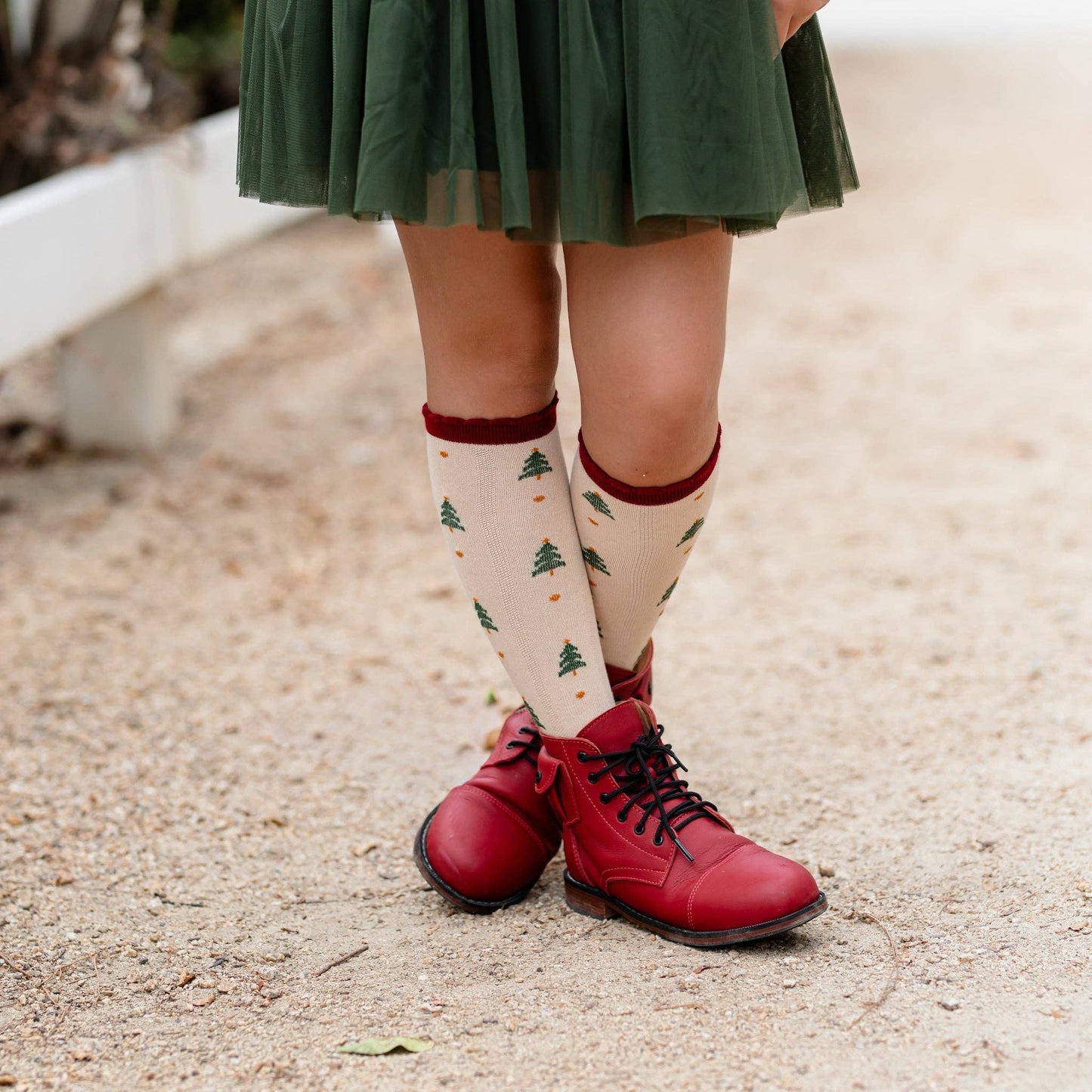 Person wearing red shoes and patterned socks on a gravel surface