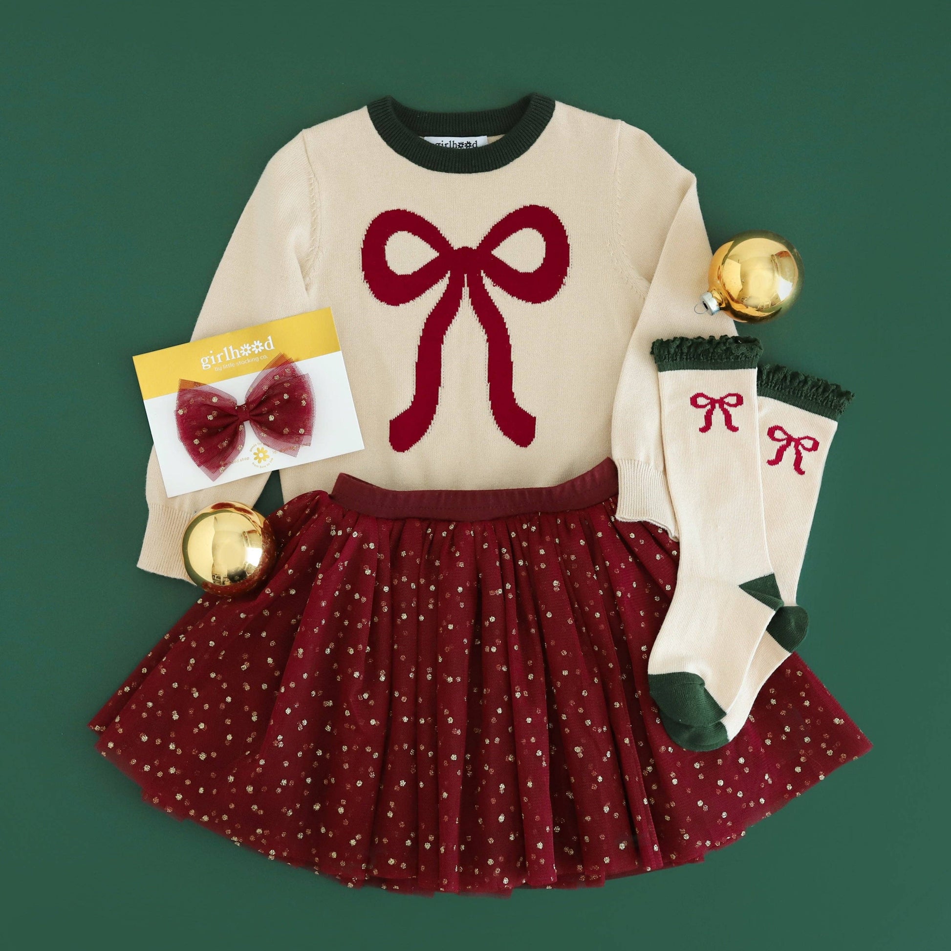 Children's outfit with sweater, skirt, socks, and accessories on a green background