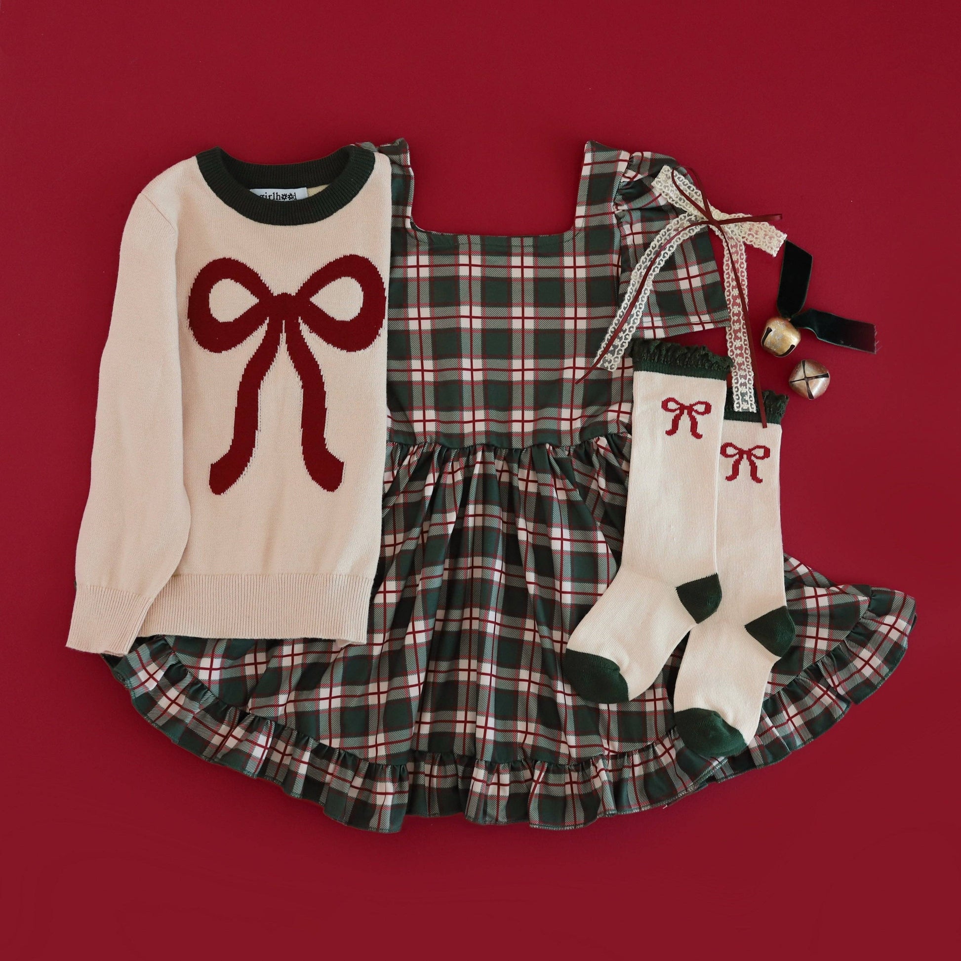 Children's outfit with sweater, dress, and socks on a red background