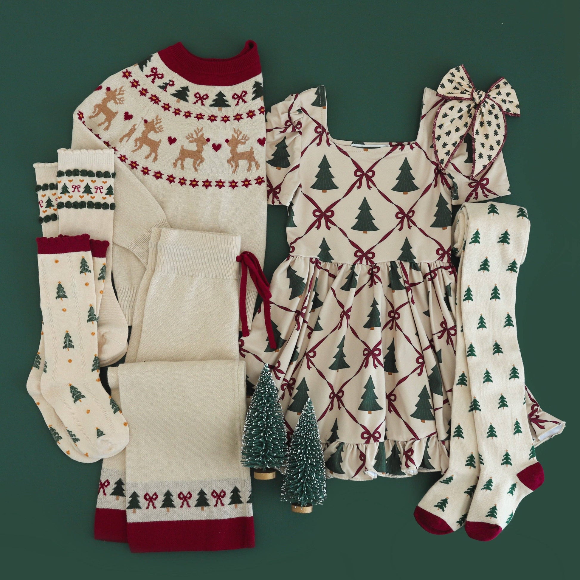 Collection of Christmas-themed children's clothing and accessories on a green background