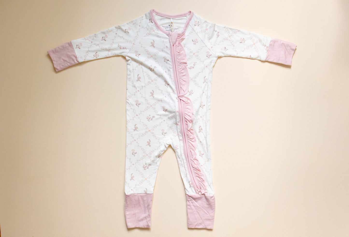 Baby onesie with pink accents on a beige background