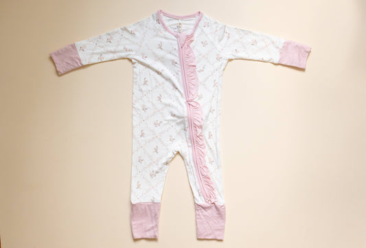 Baby onesie with pink accents on a beige background