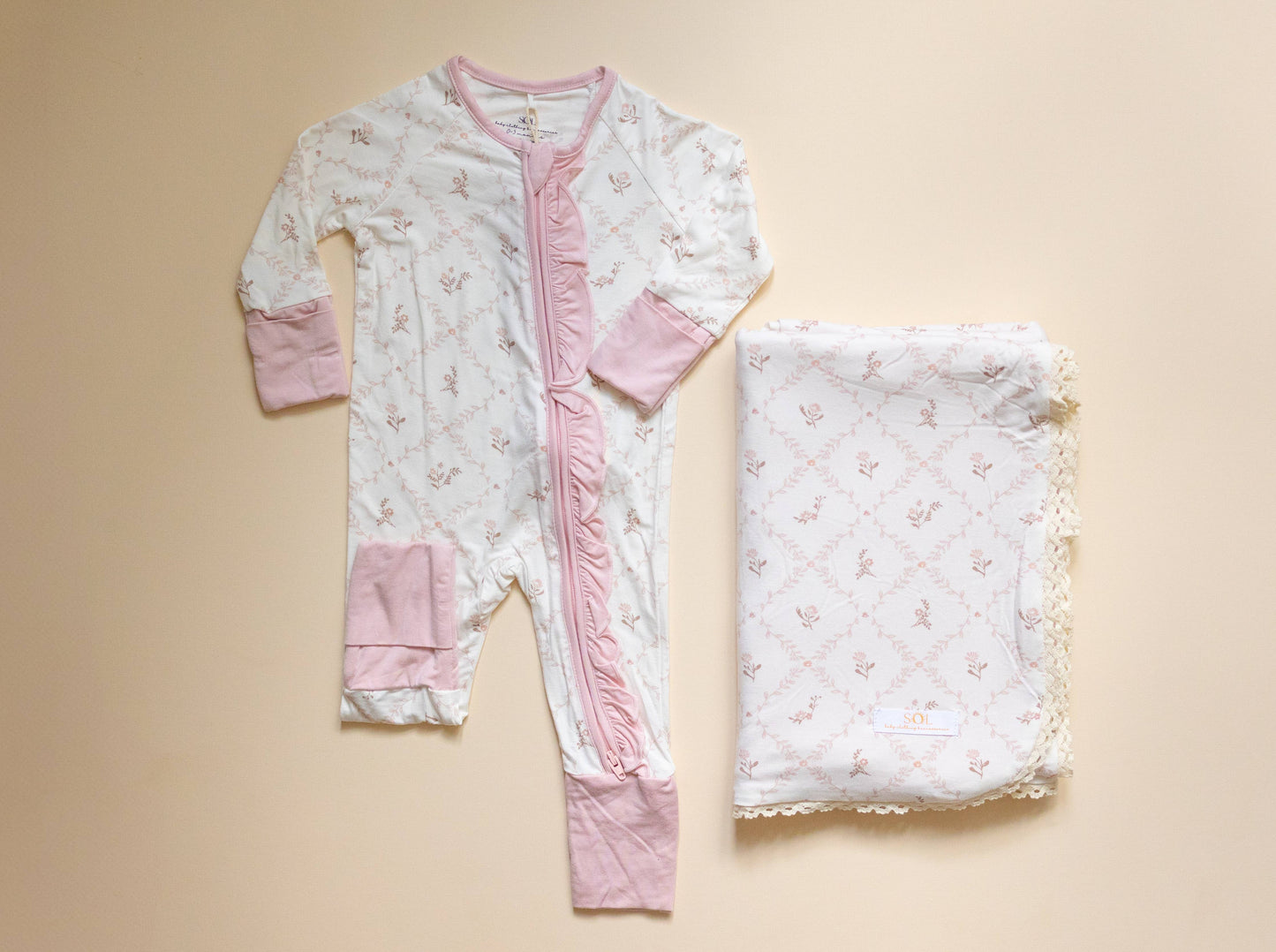 Baby onesie and blanket with floral pattern on a beige background