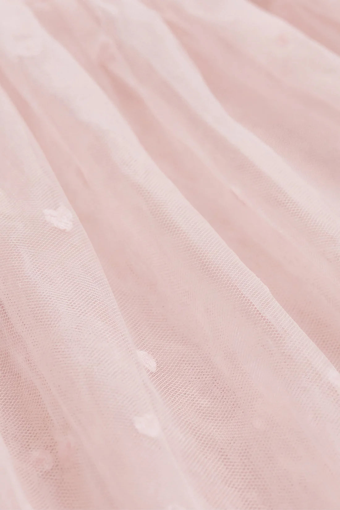 Close-up of a light blush pink tulle fabric with subtle embroidered details.